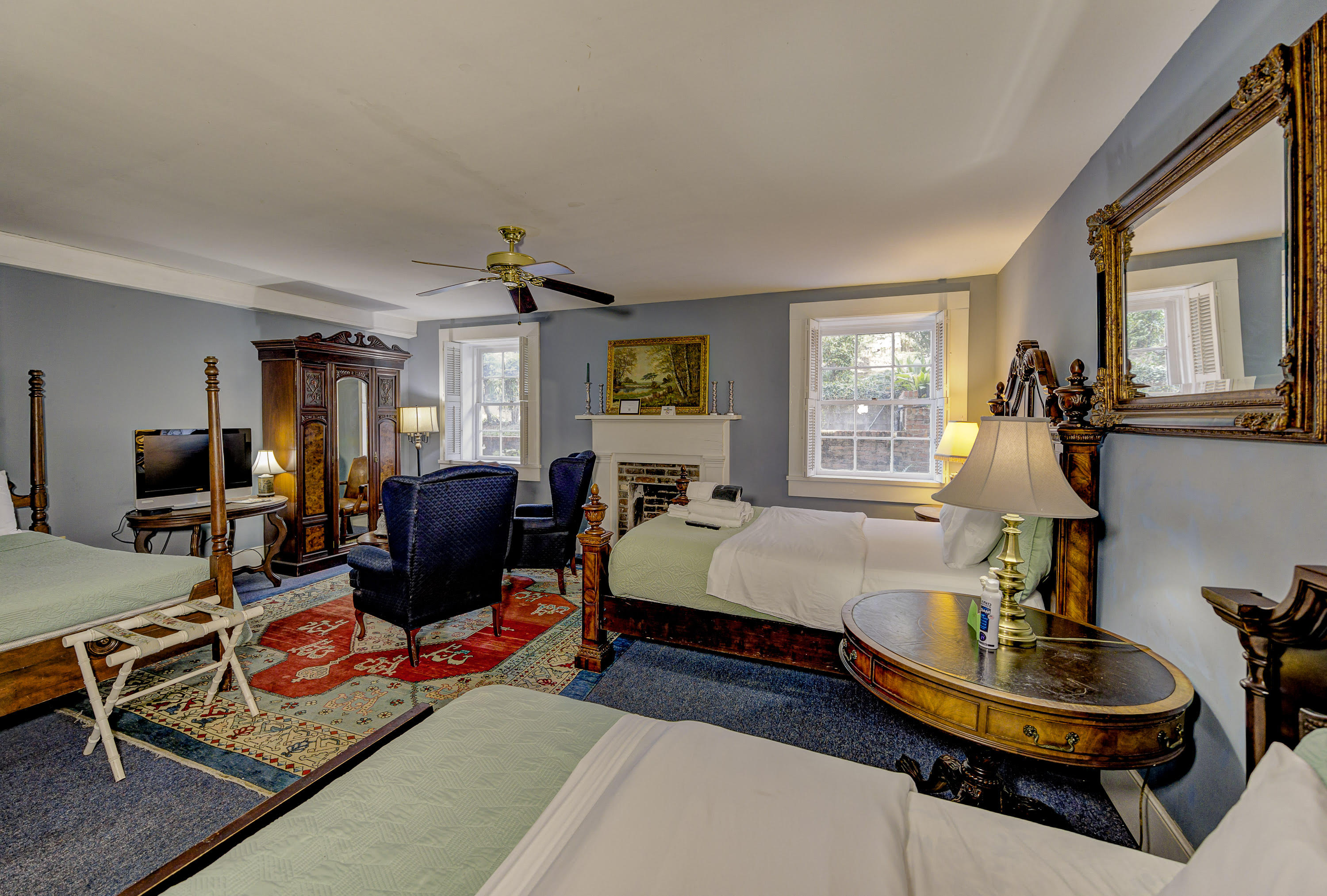 blue chintz club chair, two blue wing chairs, armoire, four poster single bed, oriental rug