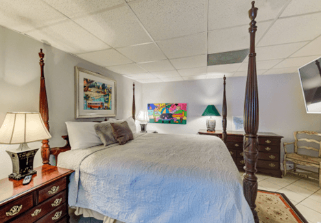 art over bed is old Holiday Inn Logo, big bed, TV, two end tables with lamps