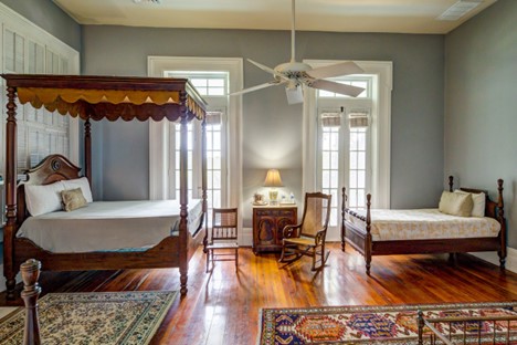 Full tester bed, two cain chairs, twin bed, oriental rugs, large doors to front porch, white ceiling fan