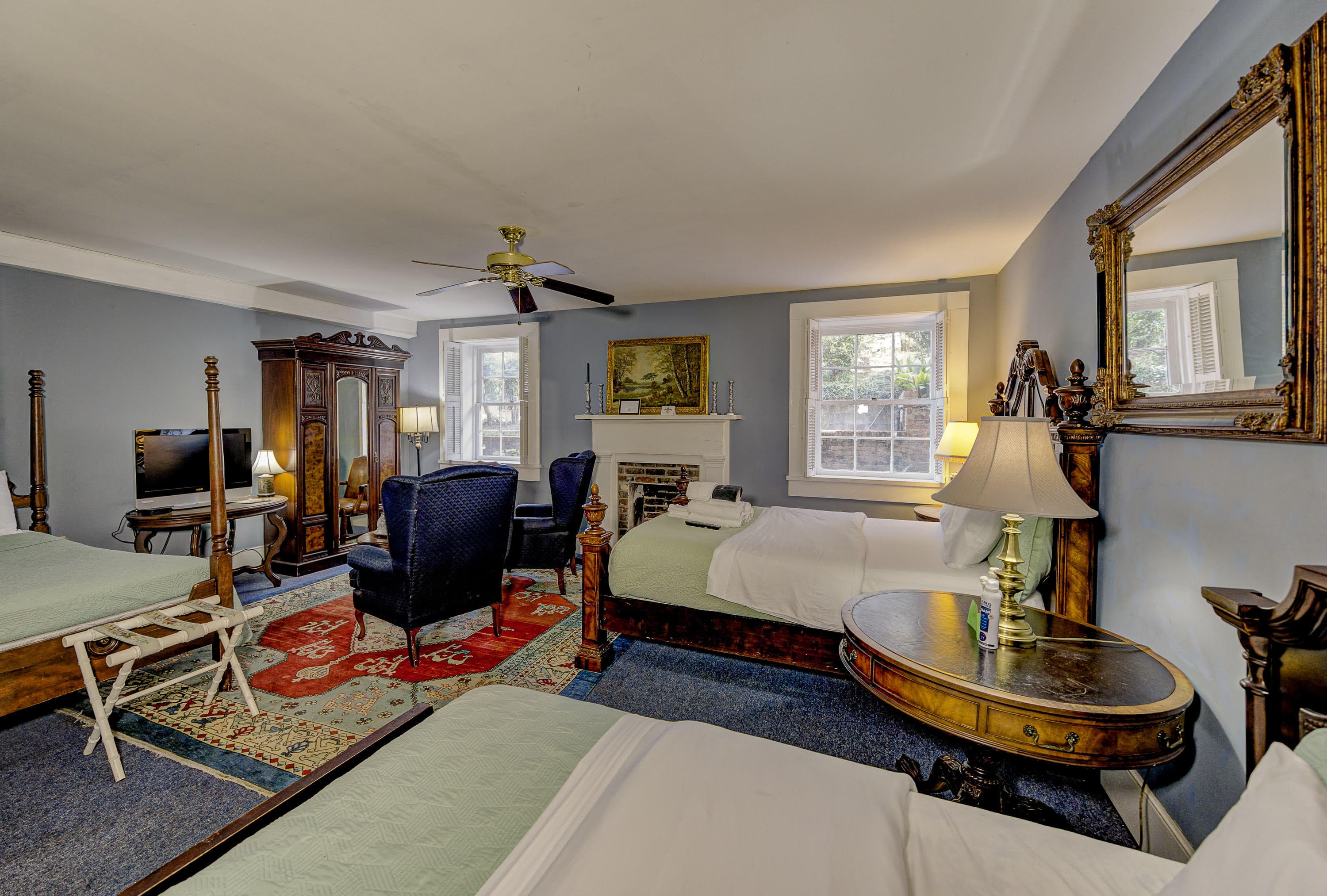 blue chintz club chair, two blue wing chairs, armoire, four poster single bed, oriental rug