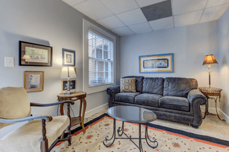 sitting room, black fold out couch, coffee table, 2 lamp tables with lamps, artwork