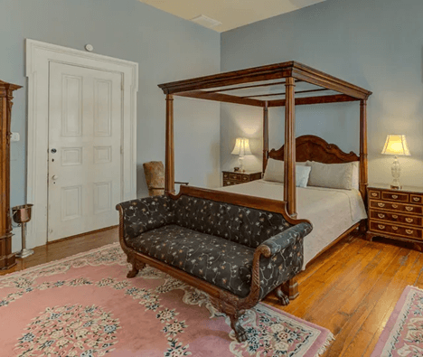 close up of sofa at foot of four poster bed, two bed tables with lamp