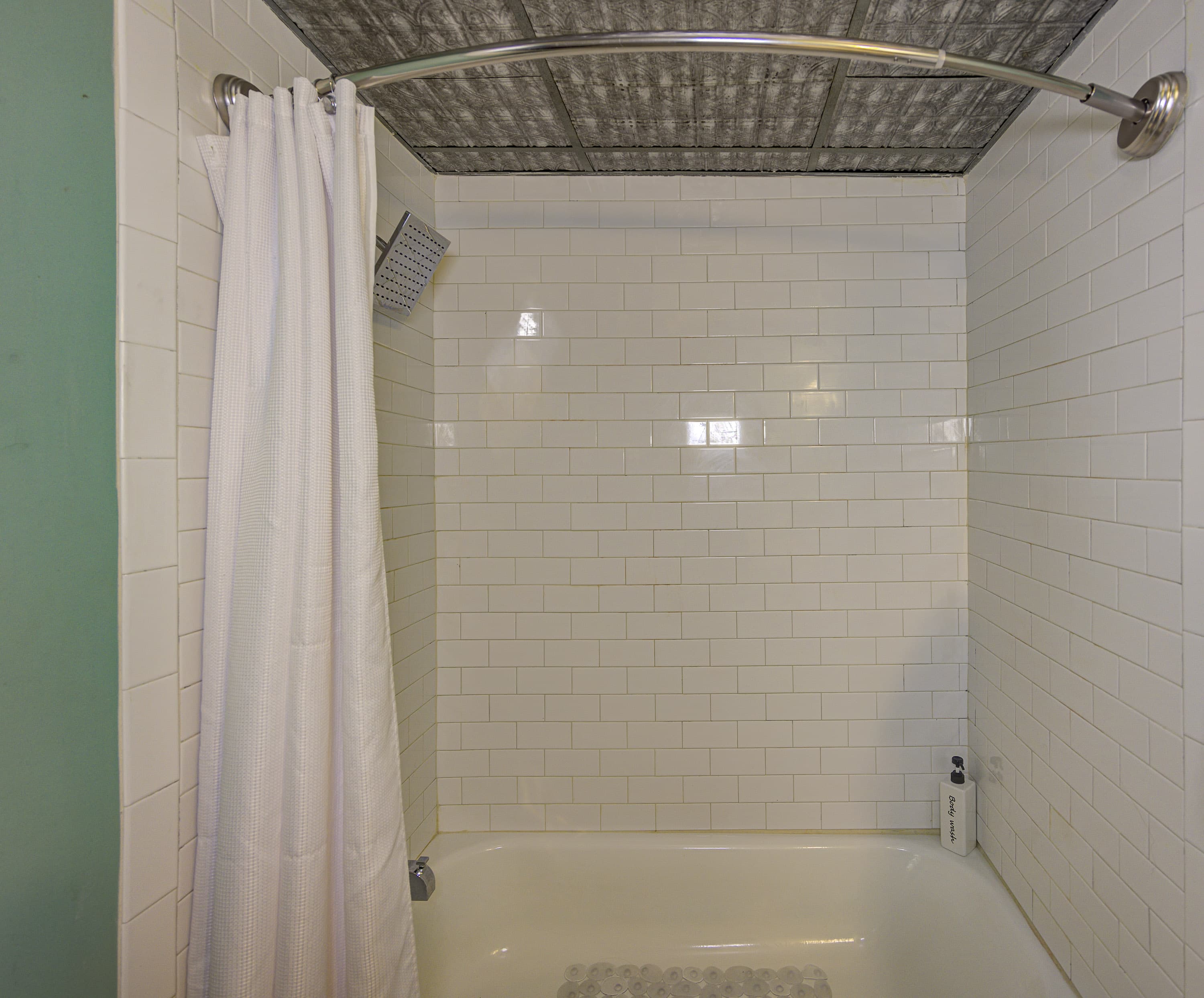 close up of tub with shower and ceramic surround