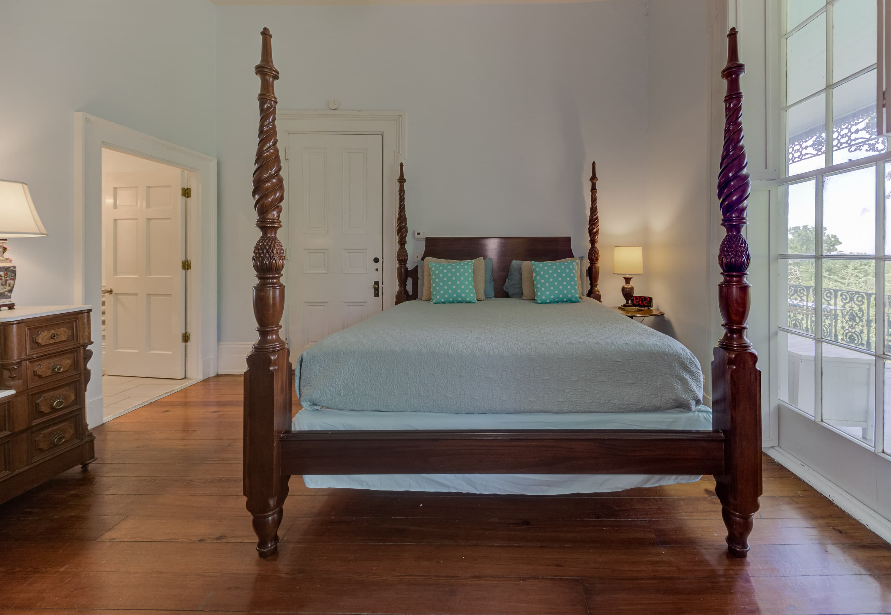 Close up of Four poster king bed, floor to ceiling windows, original hardwood floors