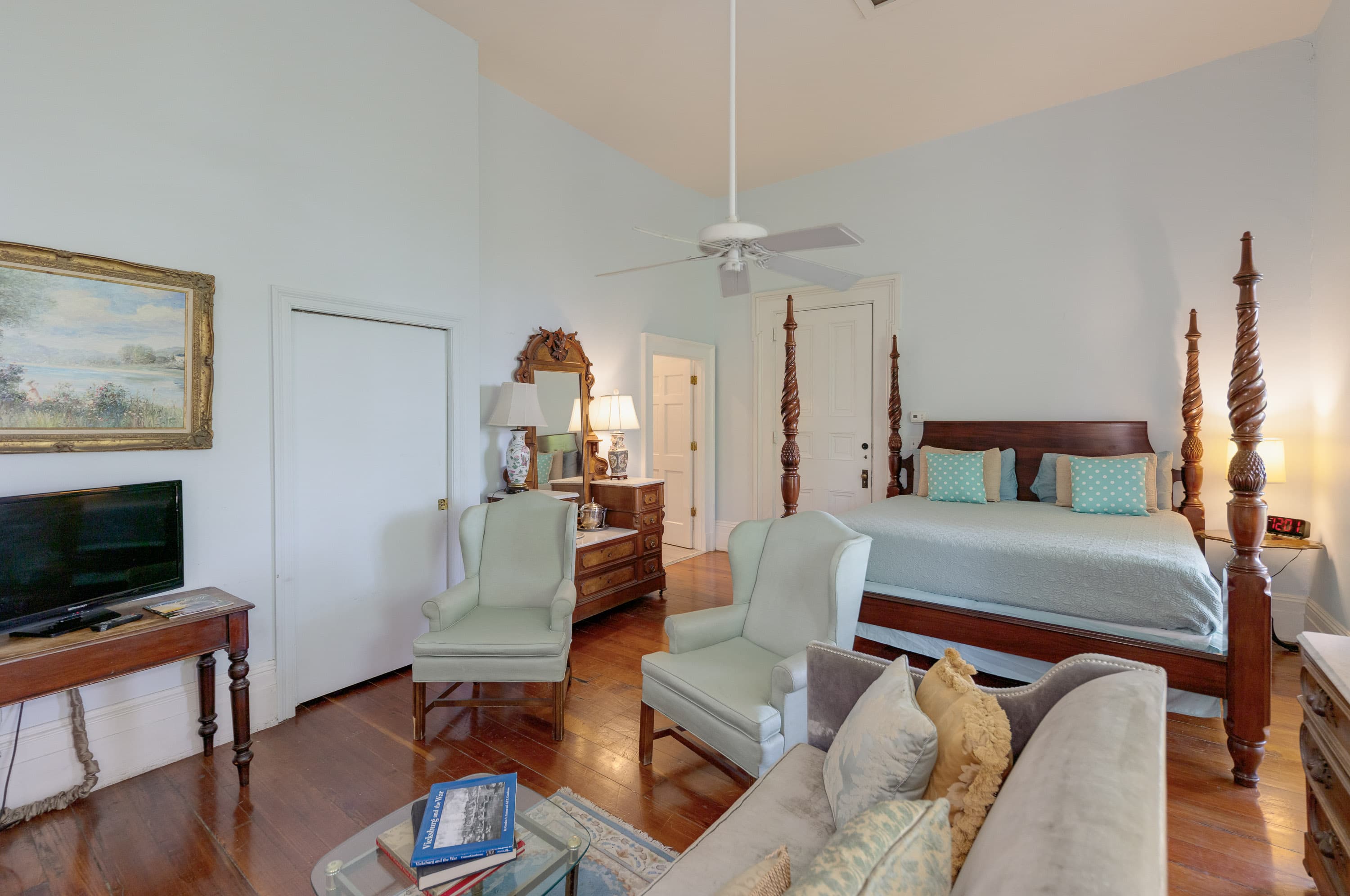 four poster bed, two chairs, TV, dresser, art