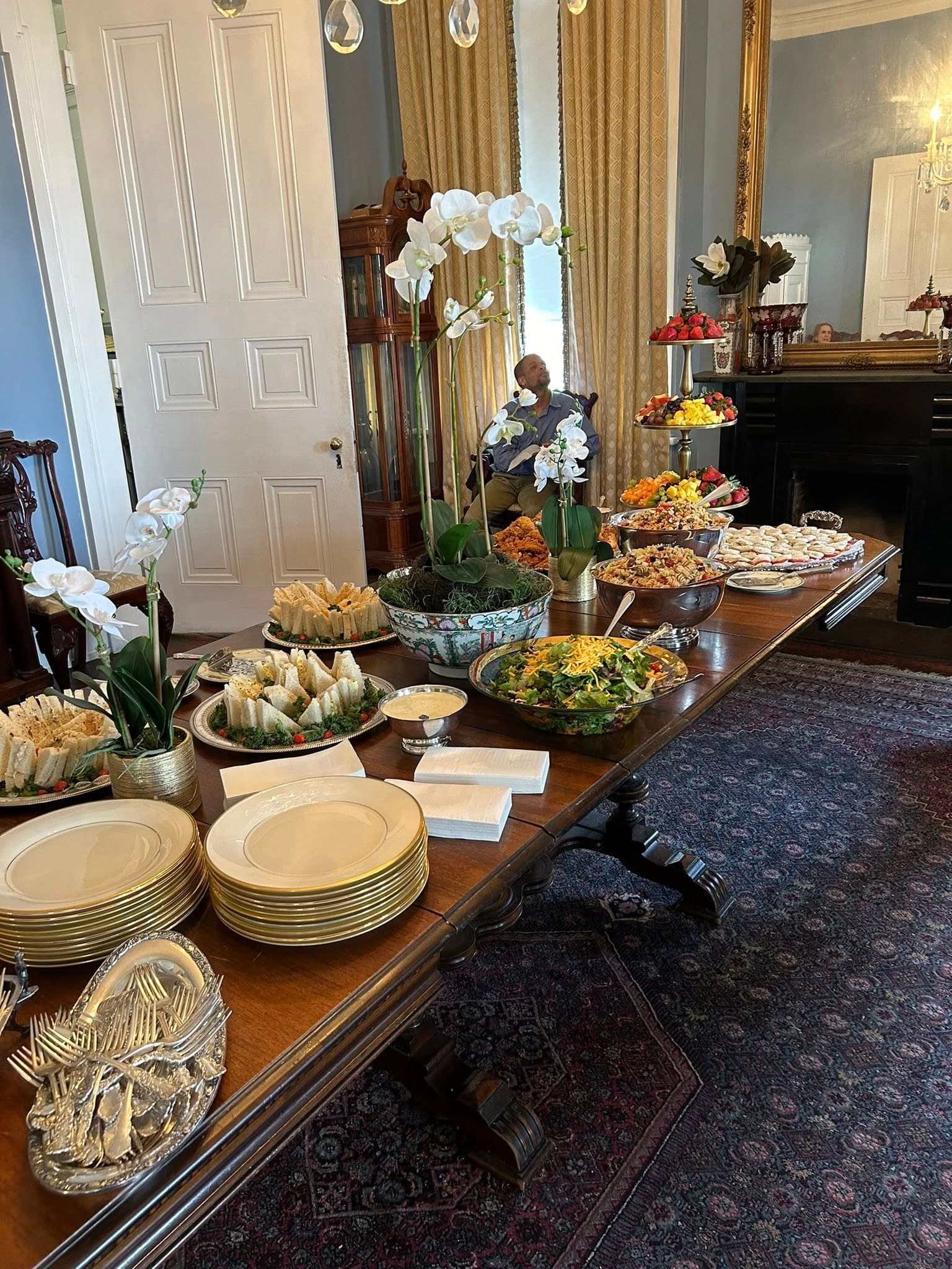 A dining table beautifully arranged with various dishes, salads, and decorative flowers in an elegant room.