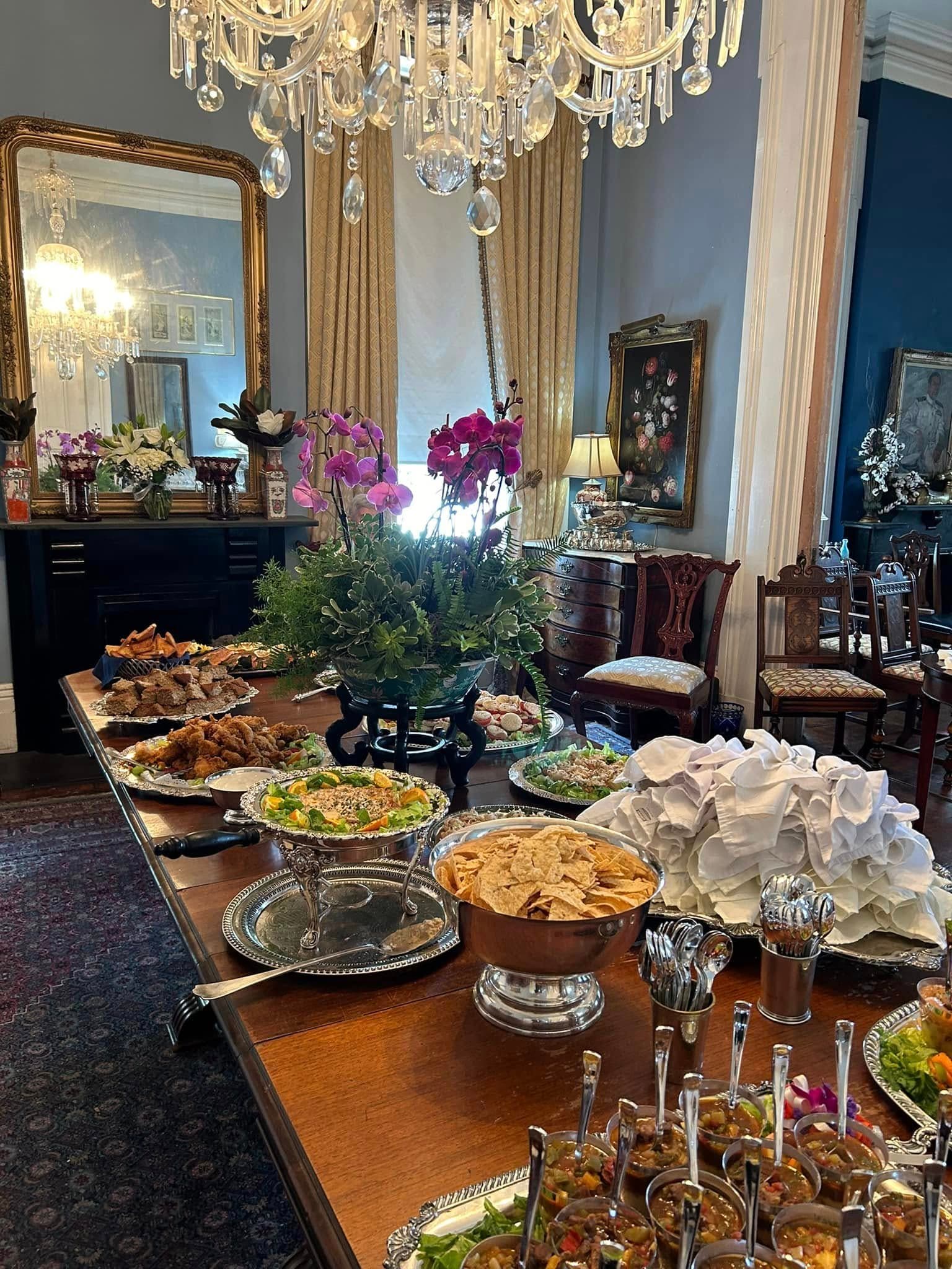 A lavishly set dining table displays an array of gourmet dishes underneath an ornate chandelier.