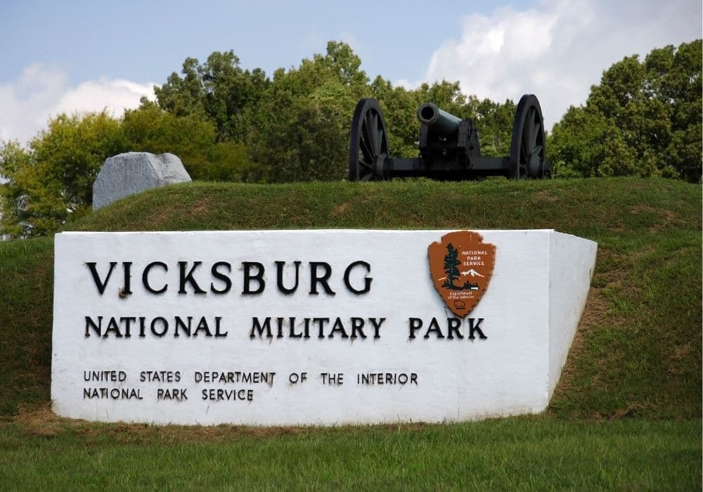 Sign for Vicksburg National Military Park featuring a cannon in the background.