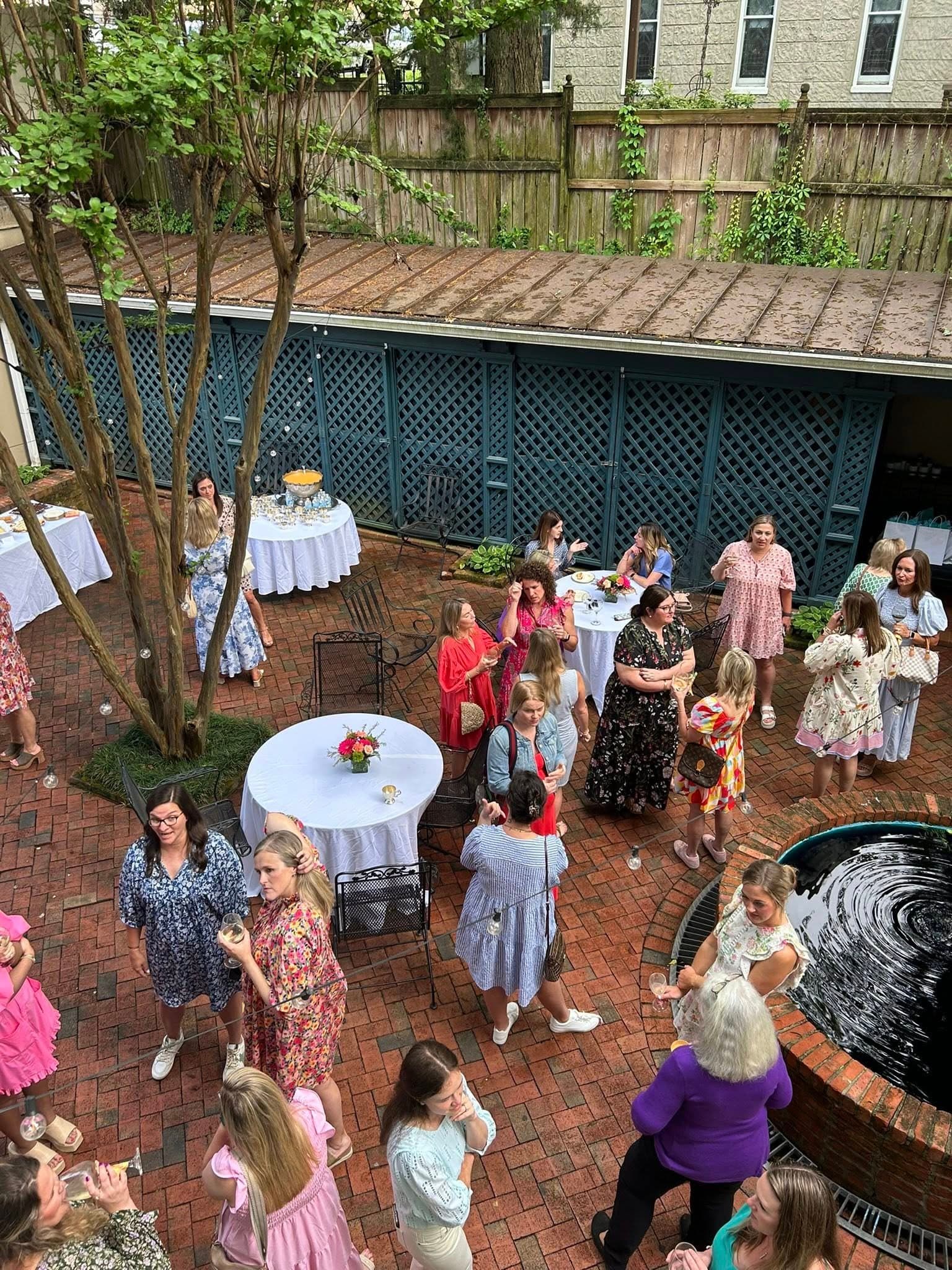 A lively outdoor gathering of women in colorful dresses enjoying drinks and conversation.