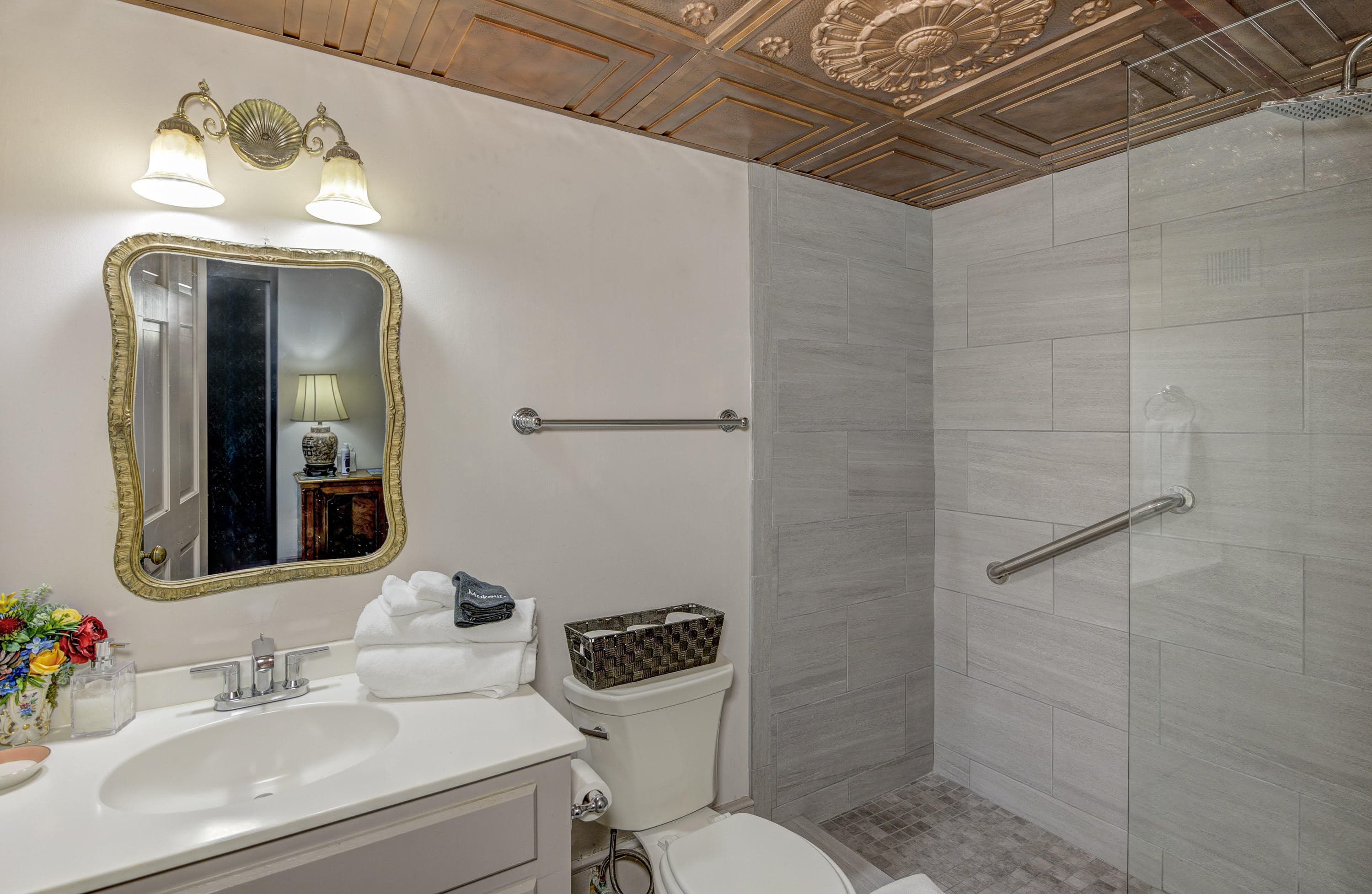 A modern bathroom featuring a shower, elegant mirror, and decorative lighting.