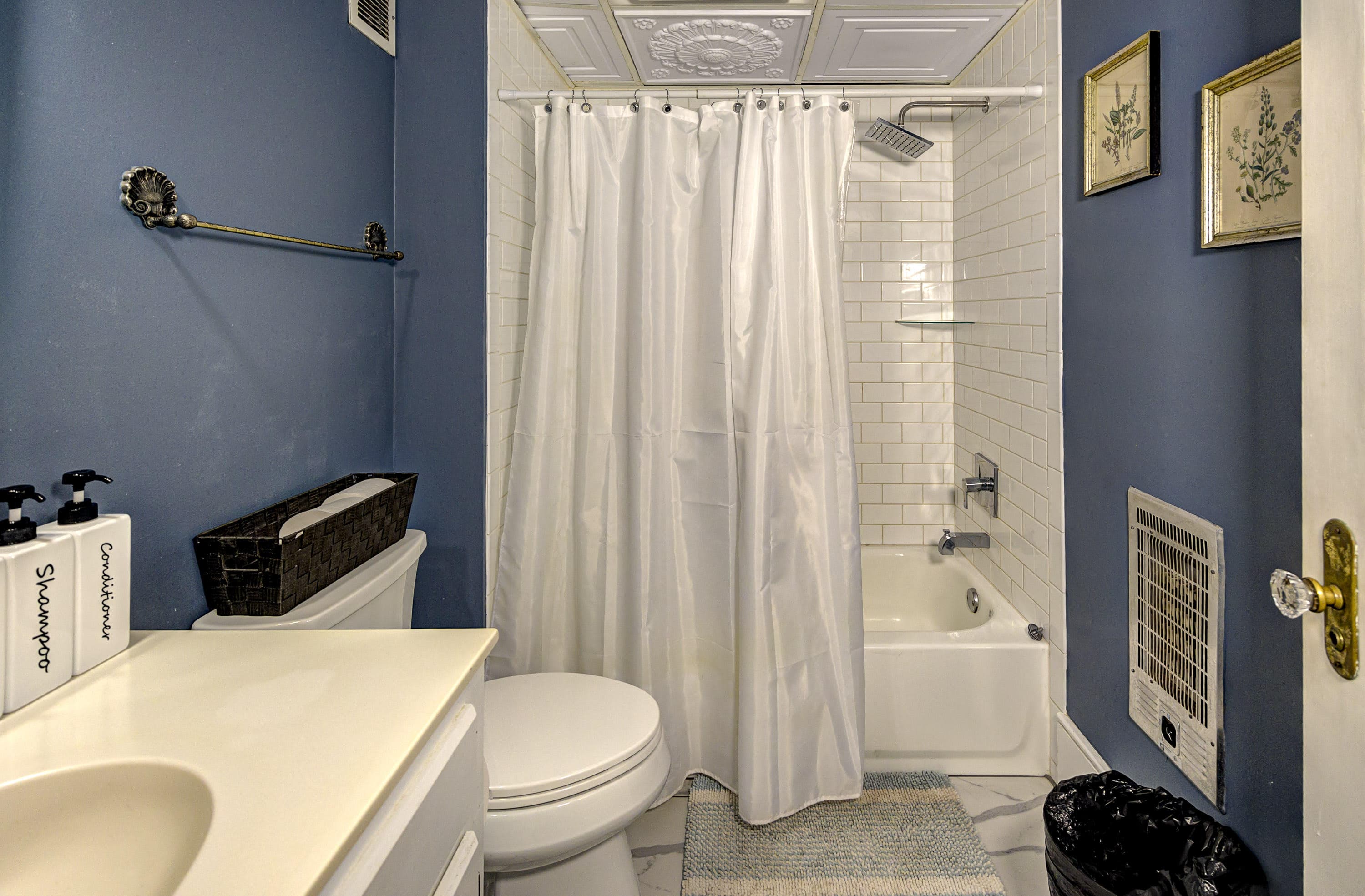 A small bathroom featuring a shower curtain, white tile, and blue walls.