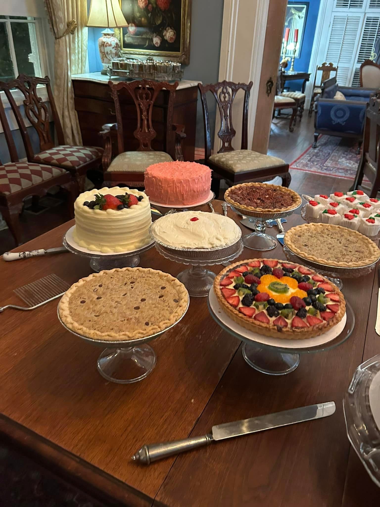 A variety of cakes and pies displayed on a wooden table.