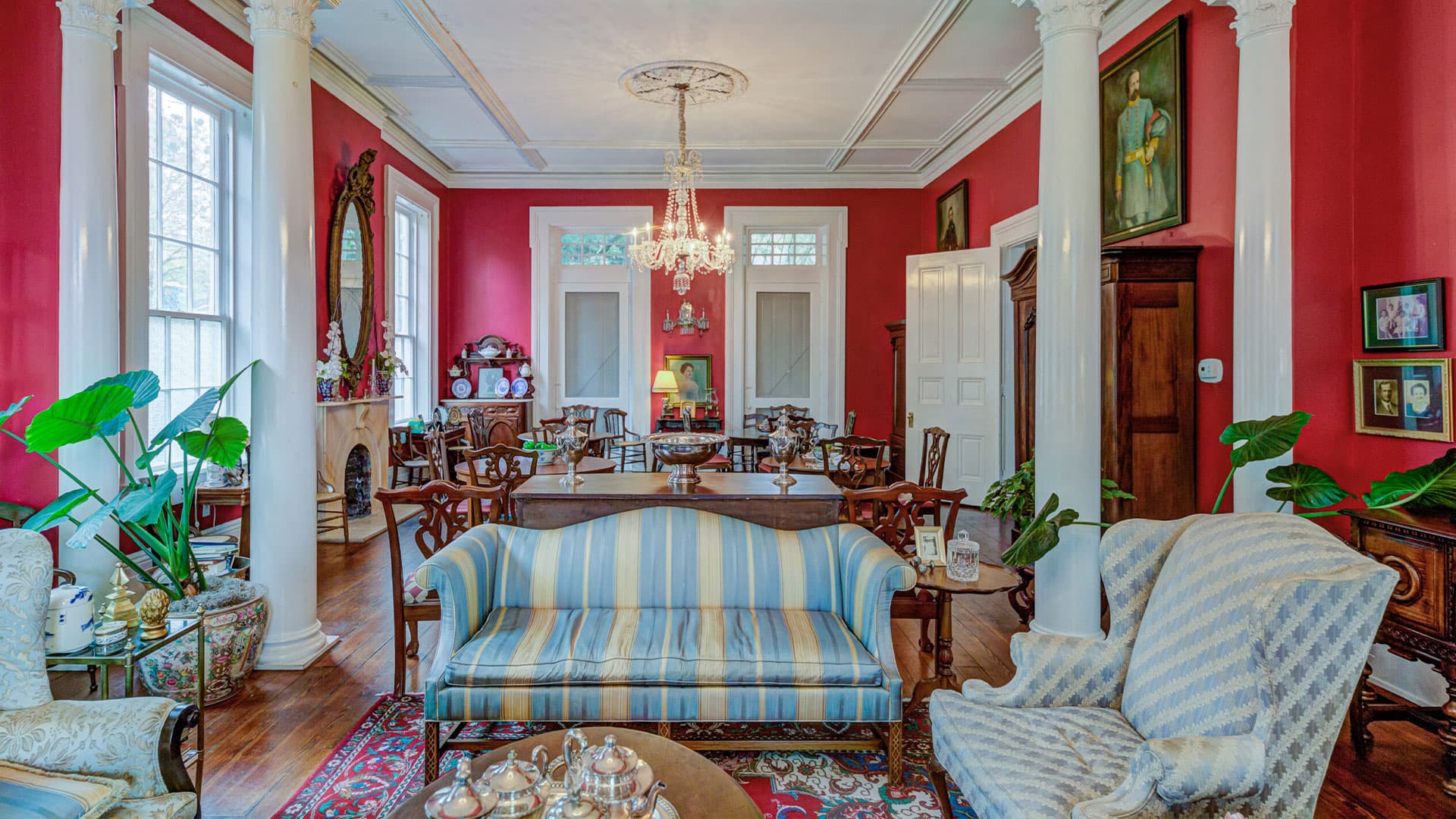 A bright red living room with classical furnishings, tall columns, and vintage decor.