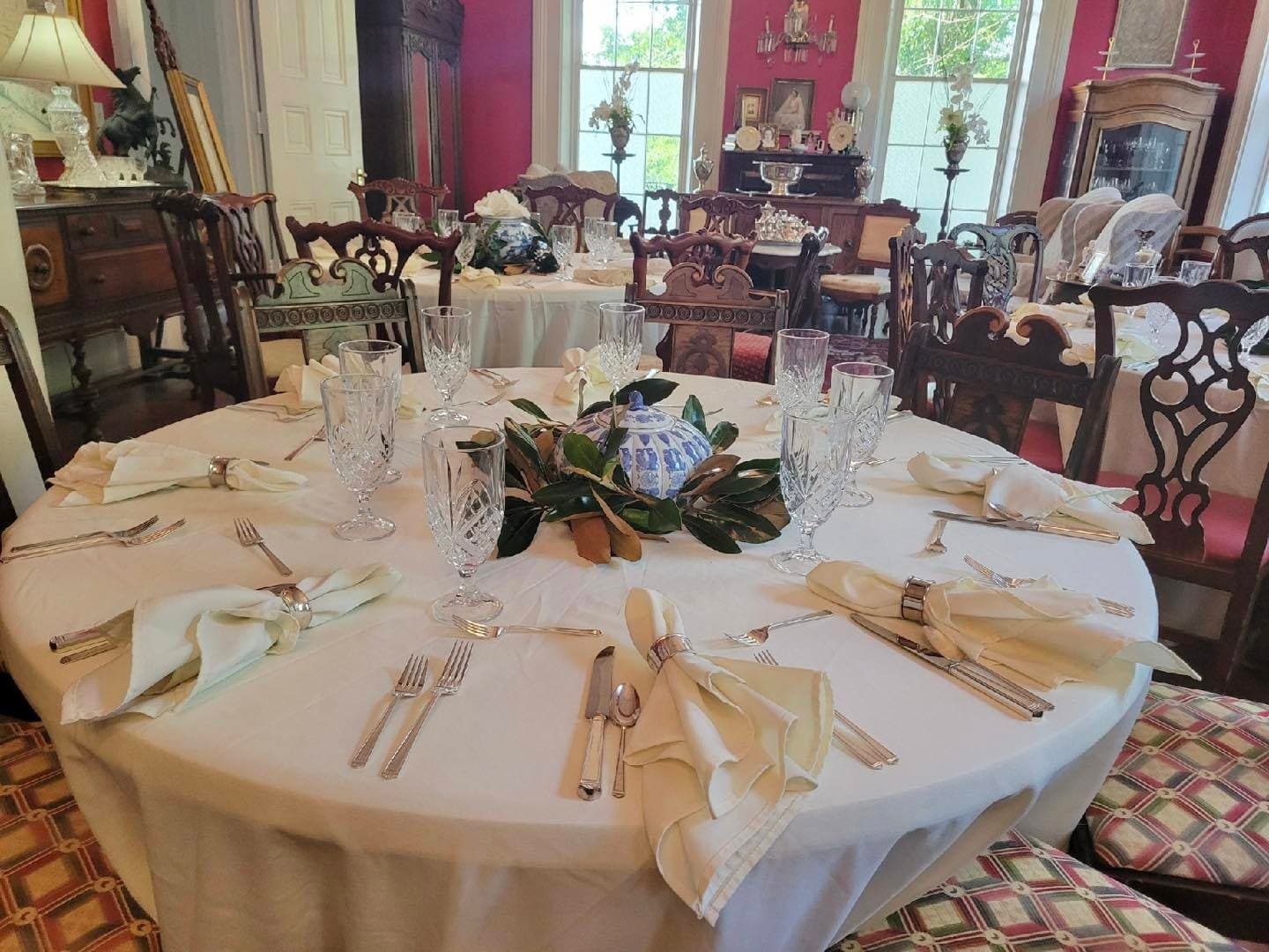 An elegantly set dining table with crystal glassware, silverware, and a floral centerpiece in a richly decorated room.